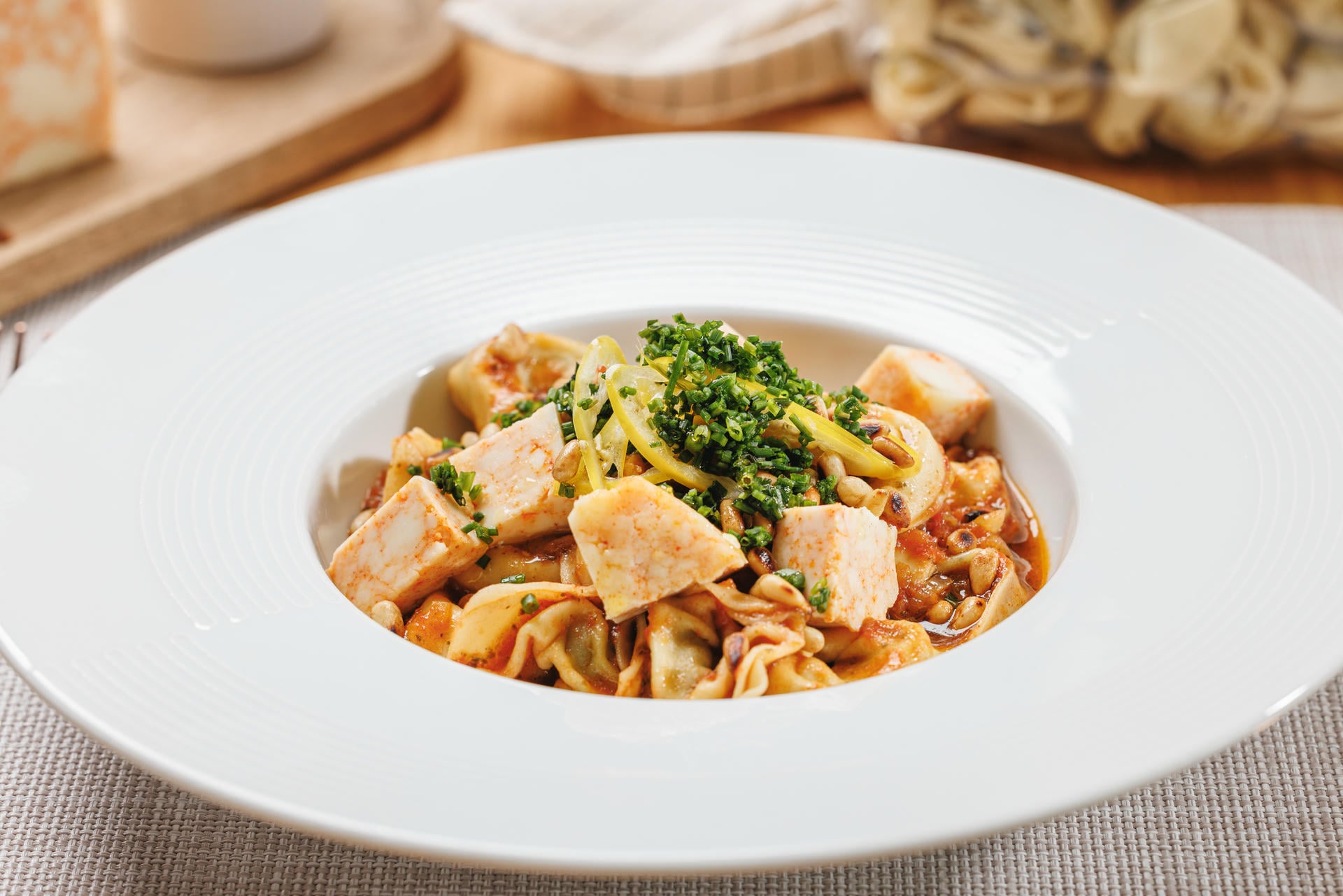 Tortelloni s ricotta sirom i špinatom, umak od rajčice, pinjoli, mladi sir s crvenom paprikom